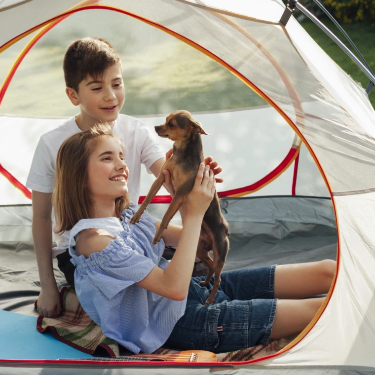 smiling-sibling-stroking-little-dog-tent-picnic-760x760.webp